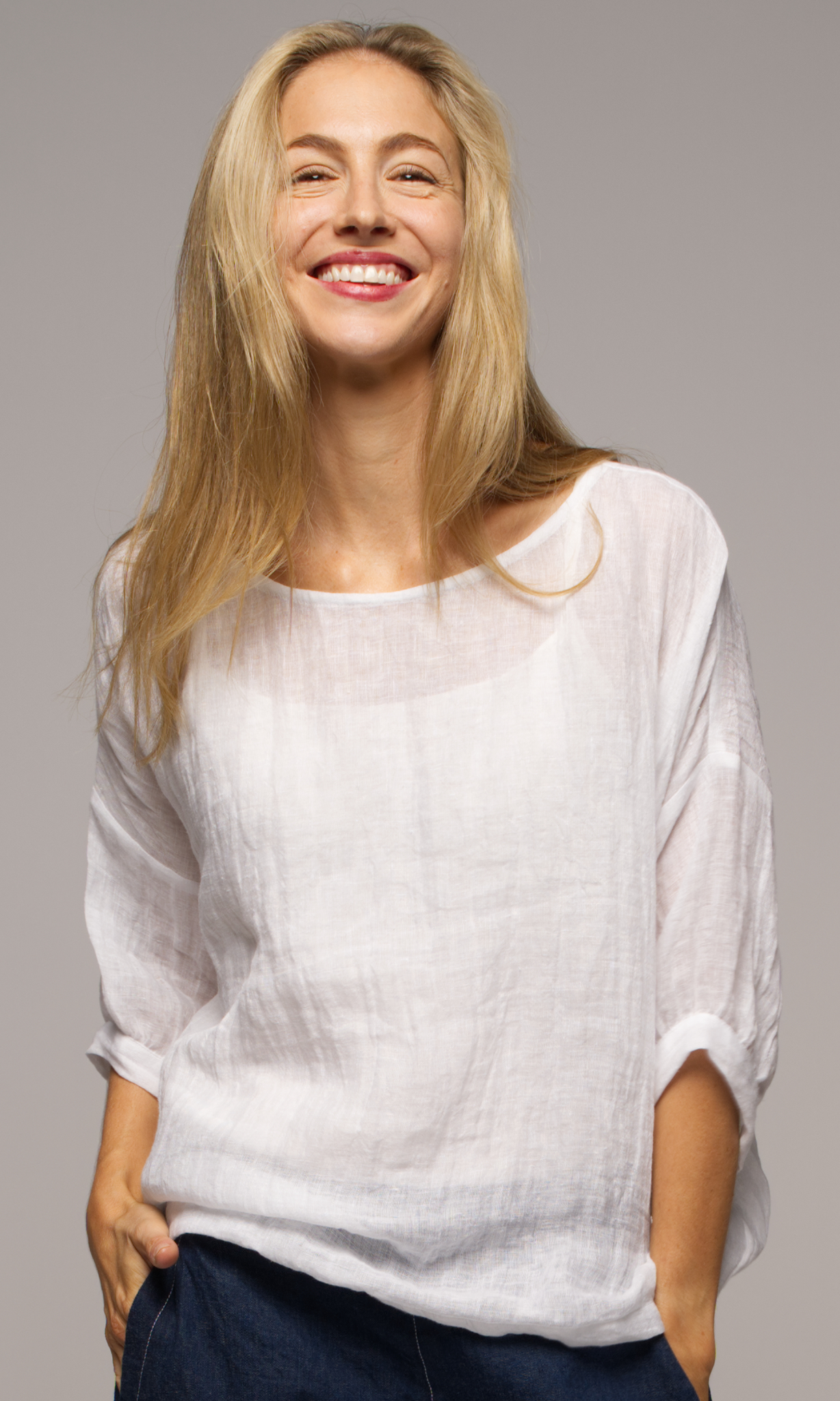 Lady wearing a white top with sleeves to elbows and dark blue coloured pants.