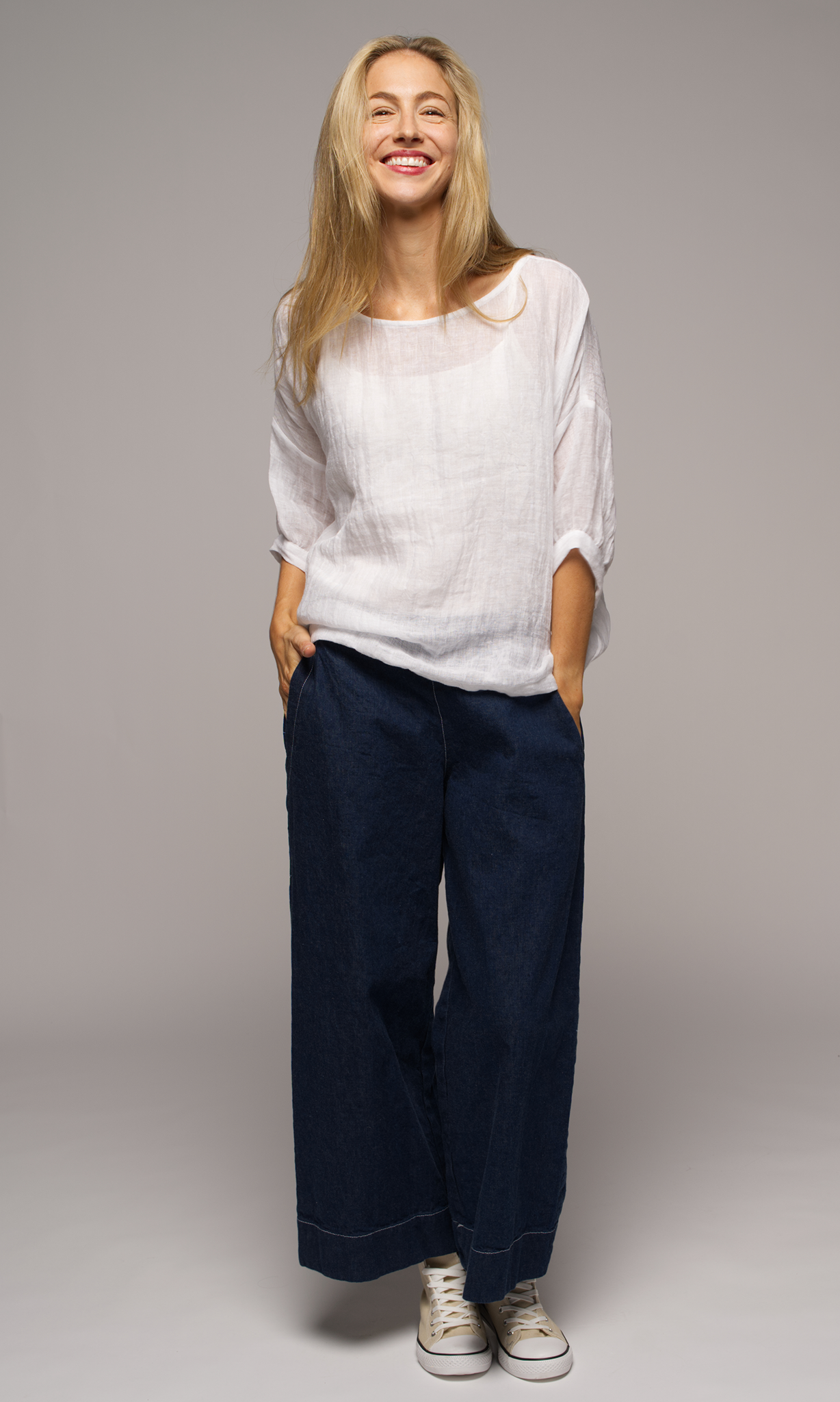 Lady wearing a white top with sleeves to elbows and dark blue coloured pants.