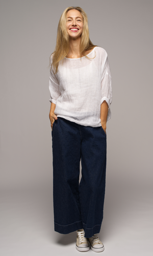 Lady wearing a white top with sleeves to elbows and dark blue coloured pants.