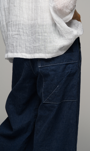 Lady wearing a white top with sleeves to elbows and dark blue coloured pants, close up on the back of the pants, showing a pocket detail.