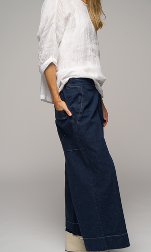Lady wearing a white top with sleeves to elbows and dark blue coloured pants, facing to the right, to show side of pants.