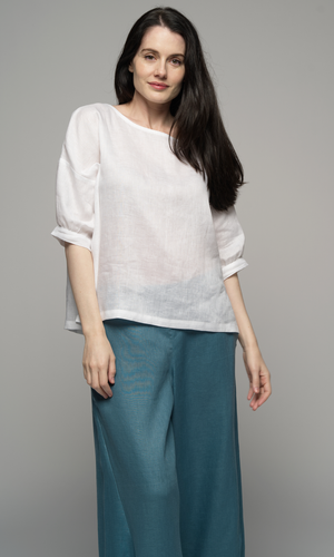 Lady wearing a white top with sleeves to elbows and a teal blue coloured ankle length pant.