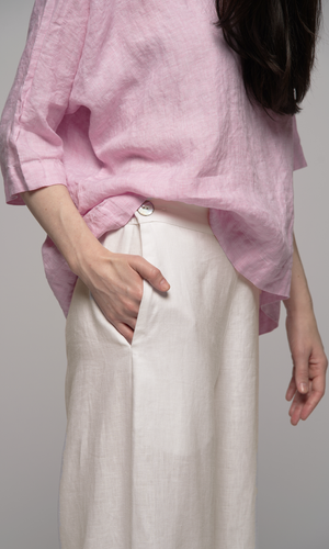 Lady wearing a 3/4 elbow length pink blouse showing pocket detail on cream coloured pants.