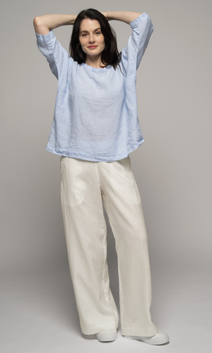 Lady wearing a 3/4 elbow length blue blouse and cream coloured pants.