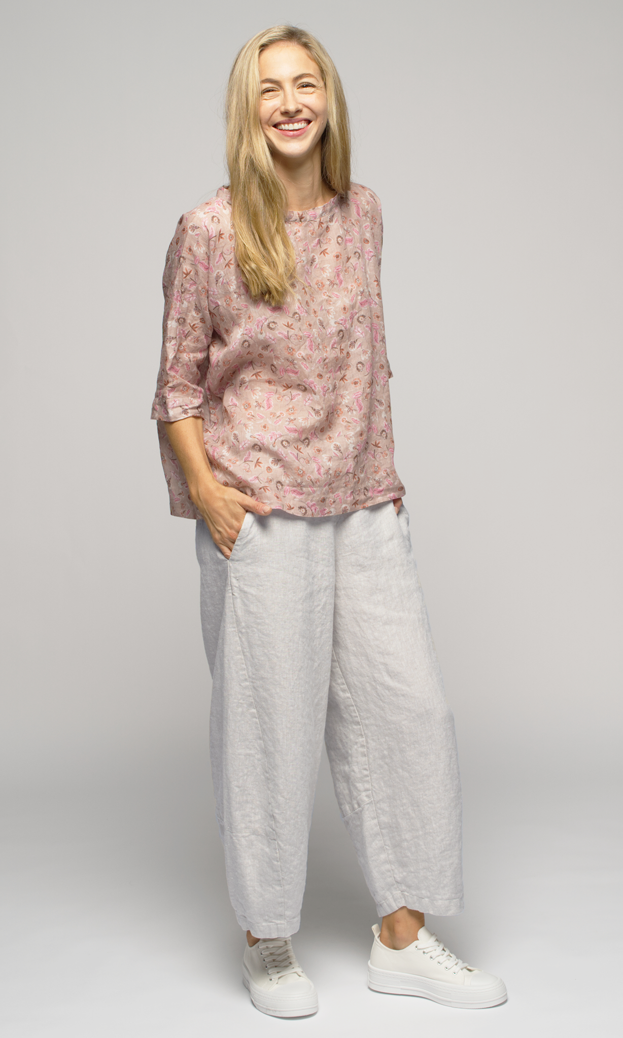 Lady wearing a floral 3/4 sleeve blouse with white ankle length pants.