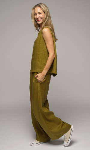 Woman wearing a olive green singlet top and pants, facing to the left.