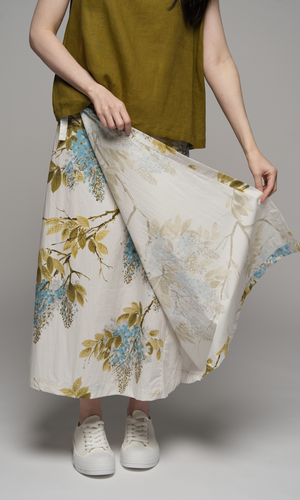 Woman wearing a olive green singlet top and a floral skirt, showing wrap detail on skirt.