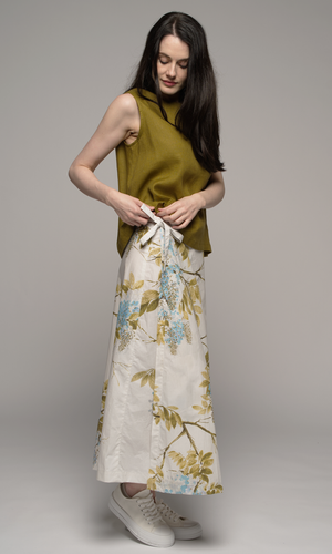 Woman wearing a olive green singlet top and a floral skirt, showing side tie detail on skirt.
