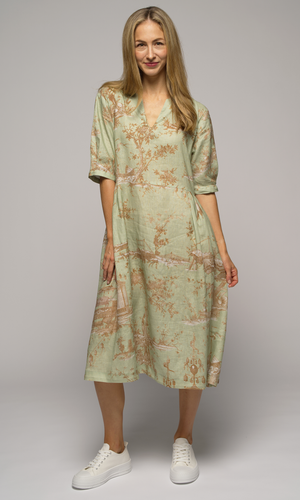 Woman wearing a light green floral dress, posing with her right hip facing out.