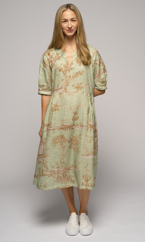 Woman wearing a light green floral dress, facing you.