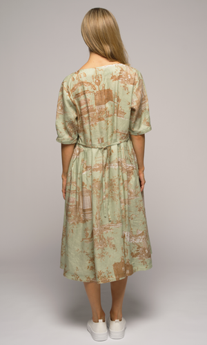 Woman wearing a light green floral dress, showing us the back of the dress.