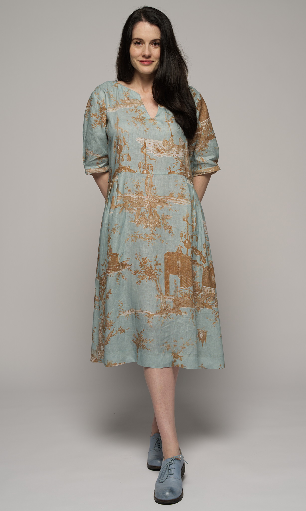 Woman wearing a light blue floral dress, facing you.