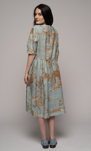 Woman wearing a light blue floral dress, showing us the back of the dress.