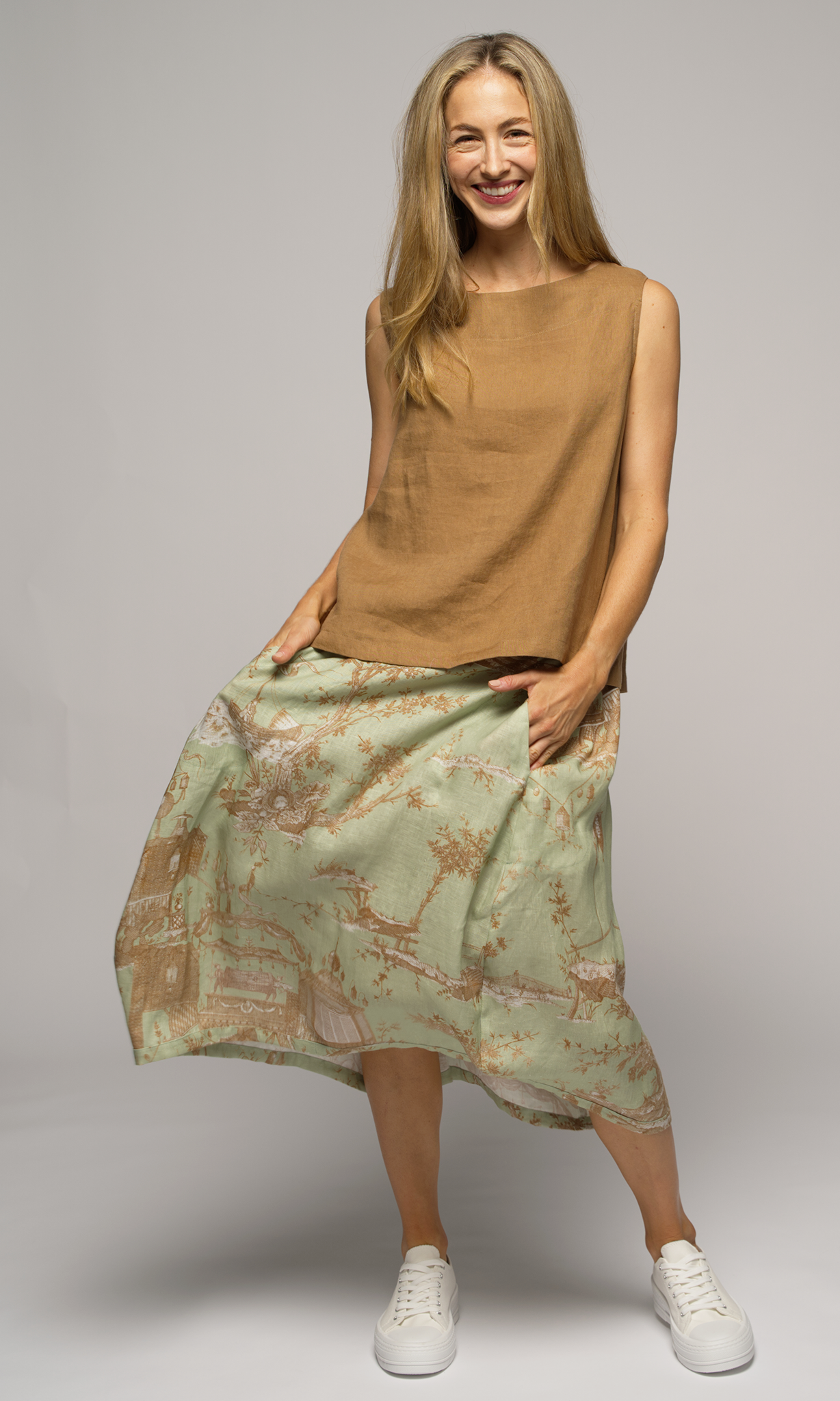 Woman wearing a light green floral skirt and a pure linen top, facing you.
