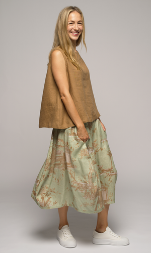 Woman wearing a light green floral skirt and a pure linen top, turned to the right.