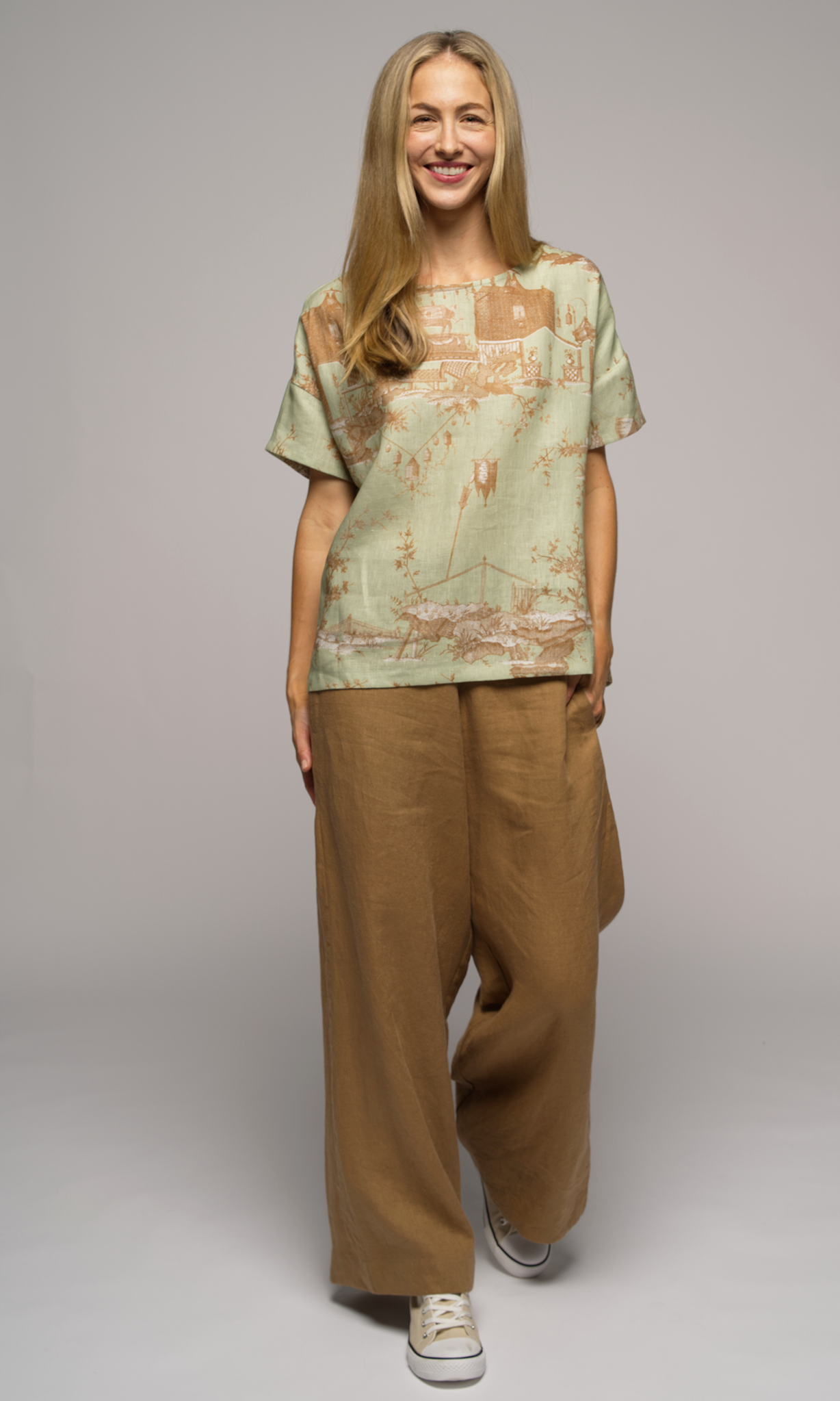 Woman wearing a light green patterned shirt and light brown pants.