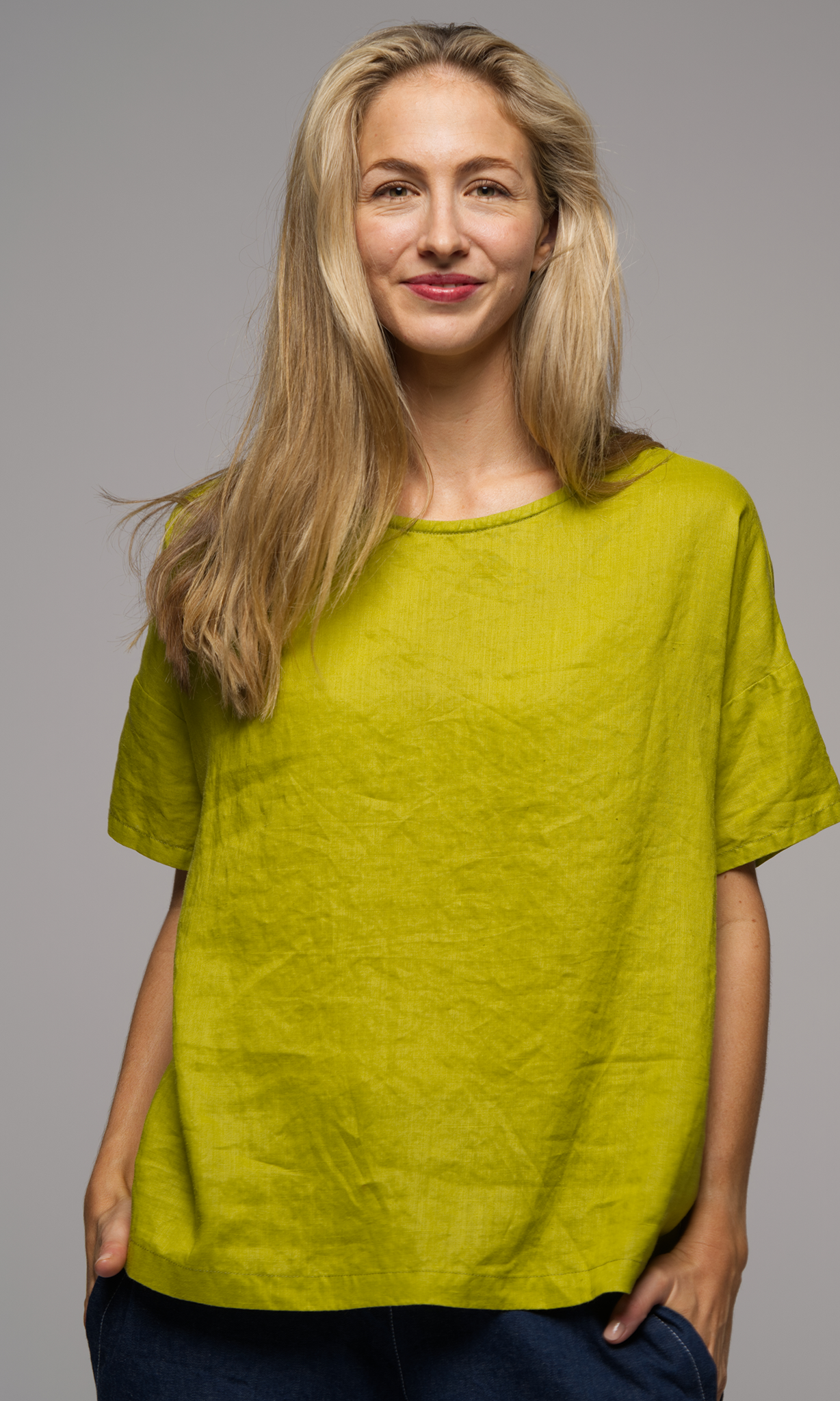 Woman wearing a greenish yellow shirt with blue denim pants.