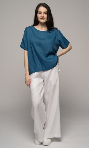 Woman wearing a blue blouse with white pants.