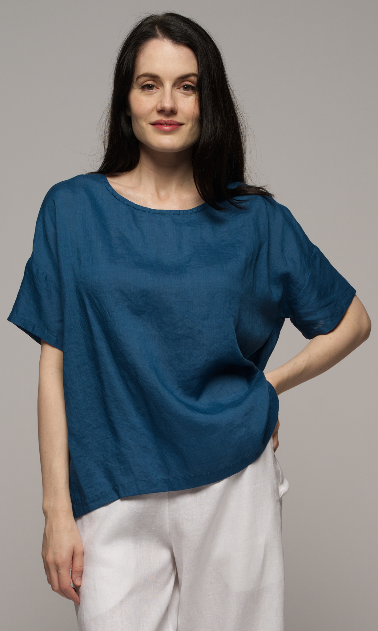 Close up of a woman wearing a blue blouse with white pants.