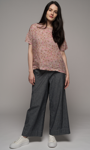 Women wearing a pink floral blouse with medium grey full length pants.