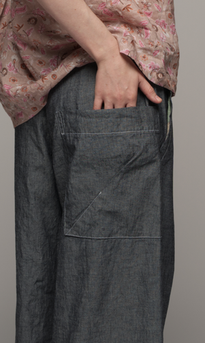 Women wearing a pink floral blouse with medium grey full length pants, close up of the pocket detail on the pants.