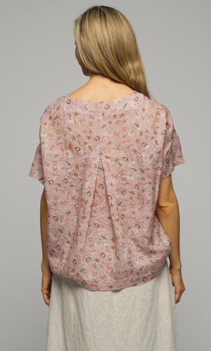 Close up of the back a woman wearing a short sleeved floral print blouse with a light cream coloured skirt.