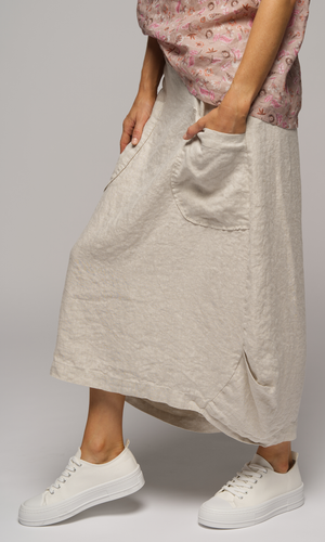 Close up of a woman wearing a short sleeved floral print blouse with a light cream coloured skirt, with big pockets.