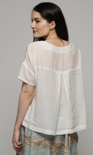 Woman wearing a white blouse with a blue patterned skirt, showing you the back of the garments.