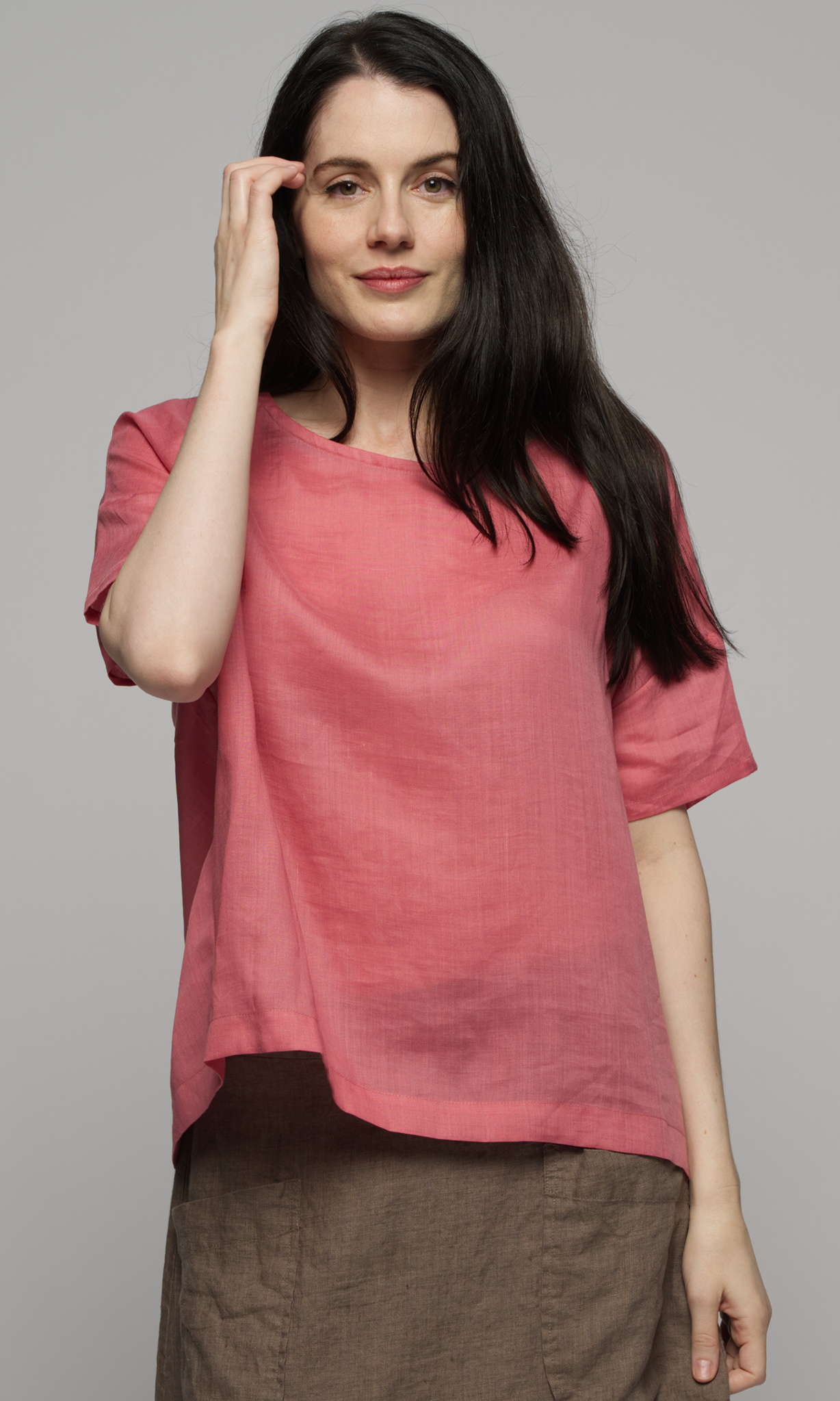 Woman wearing a pink linen top and brown linen skirt.