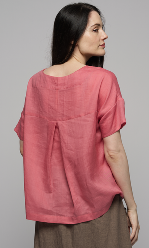 Woman wearing a pink linen top and brown linen skirt, showing you the back of the garment.