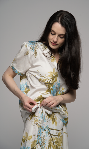 Woman wearing a floral short sleeve top and a floral skirt, showing side tie detail on skirt.